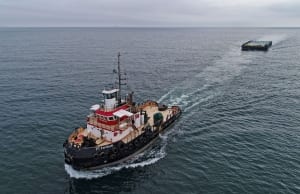 tugboat on blue ocean with crew visible on deck